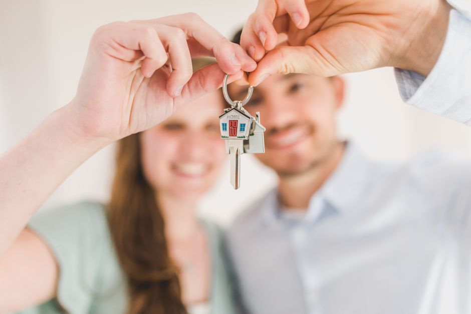 Pareja joven feliz mostrando la llave de su nuevo hogar